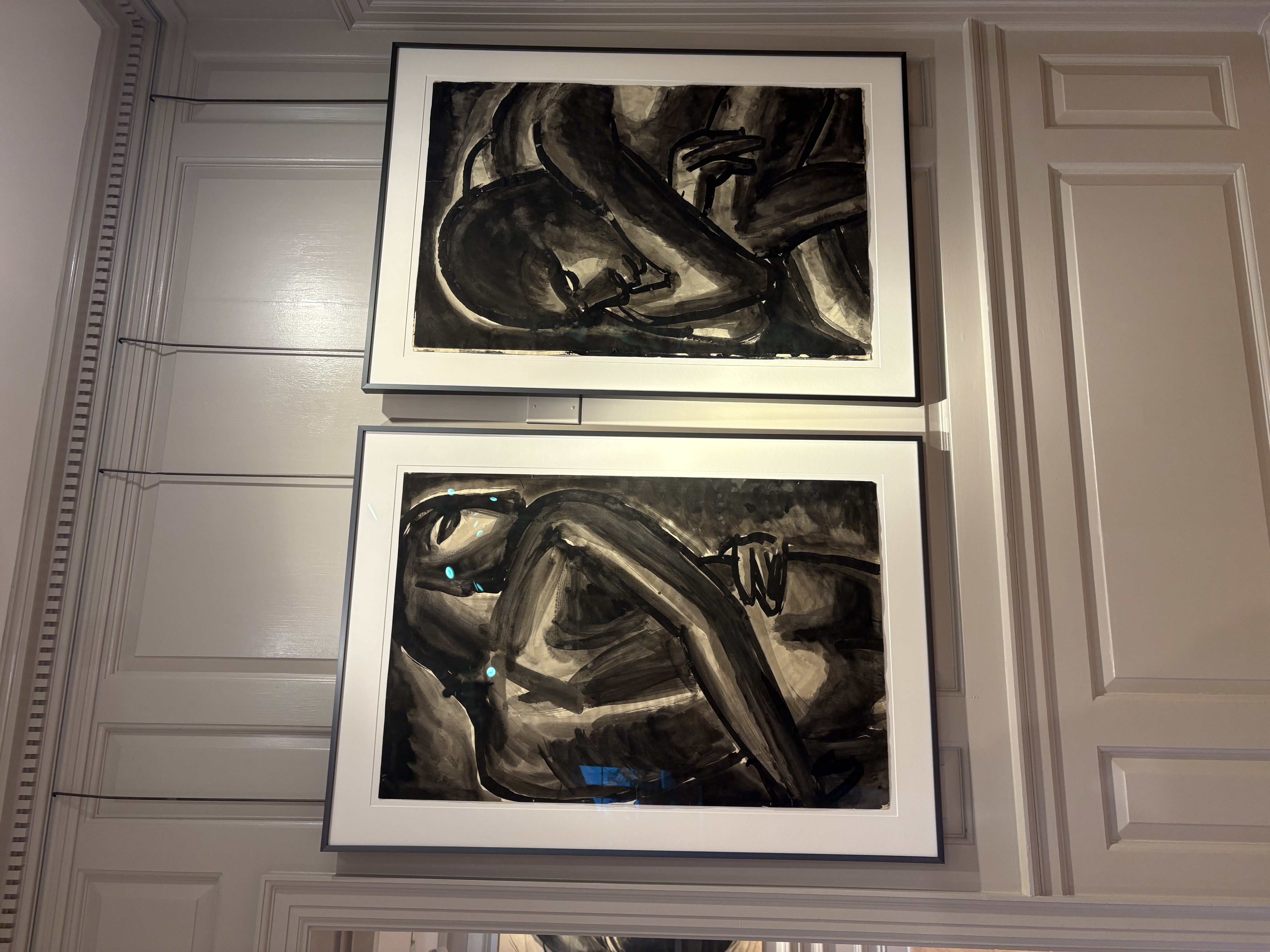 Two reclining figure works hung in a stacked arrangement