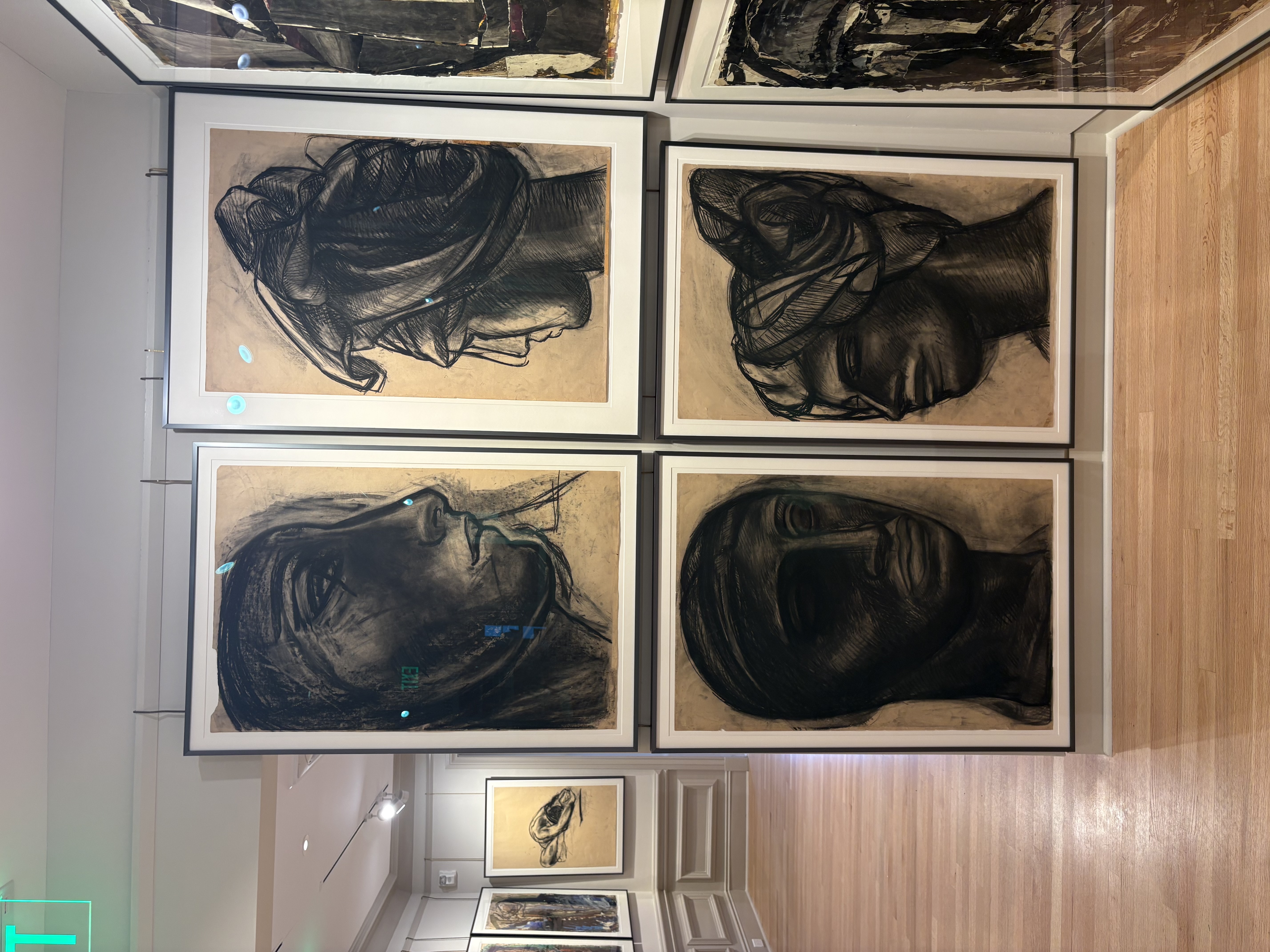 Four large charcoal head portraits in a two-by-two arrangement